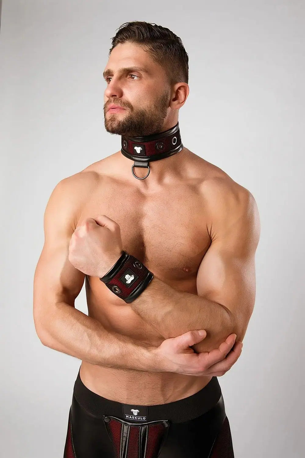 Maskulo Armored Color-Under red wristband for men, featuring black mesh and faux leather piping with metal grommets, appealing to fitness and international party-goers