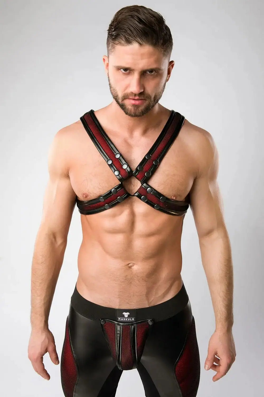 Maskulo red mesh chest X-harness for men, with black see-through 3D mesh and red color-under padding, trimmed with faux leather piping, appealing to leather fetish and puppy subculture fans